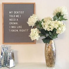 a vase filled with white flowers sitting on top of a table next to a sign