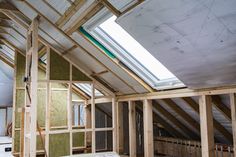 an unfinished room with wooden framing and skylight