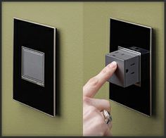 a person pressing the switch button on a green wall with two black and silver switches