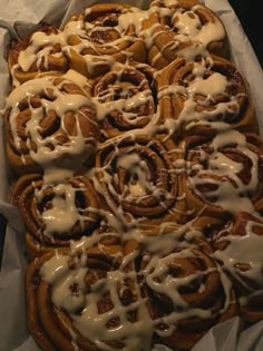 cinnamon rolls with icing sitting on top of white paper