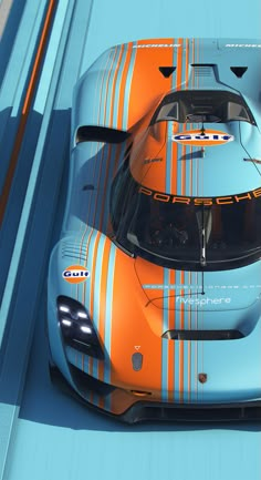 an orange and blue sports car driving down a track