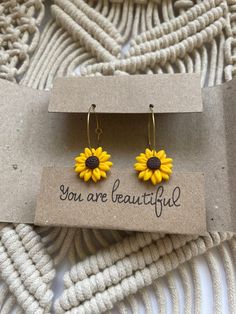 a pair of yellow sunflower earrings sitting on top of a card