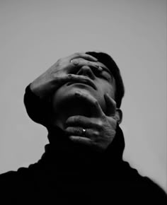 black and white photograph of a man's face with his hands on his head