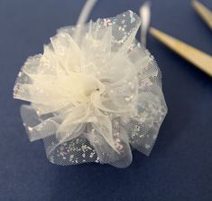 a pair of scissors sitting next to a white flower on a blue tablecloth with sequins