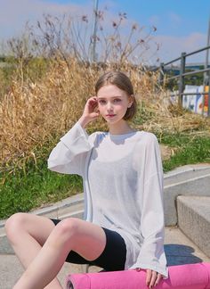 a young woman sitting on the ground with her skateboard in front of her face