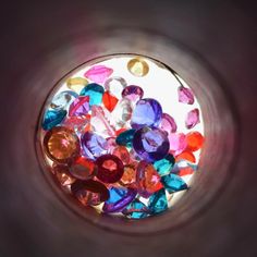 there are many different colored stones in the glass bowl on the table or shelf, as seen from above