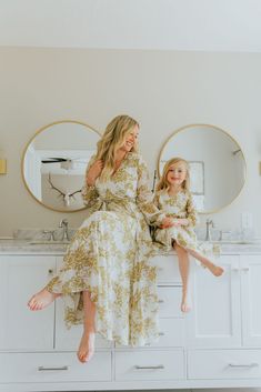 mother and daughter sitting on vanity in bathroom