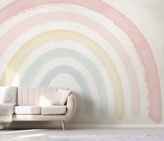 a white couch sitting in front of a wall painted with pastel rainbows on it