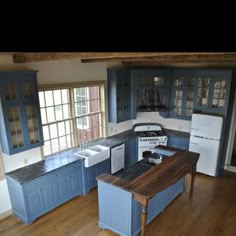 a kitchen with blue cabinets and an island in the middle is shown from across the room