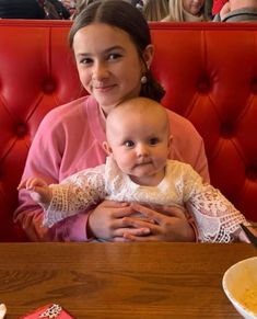 a woman sitting at a table with a baby in her lap