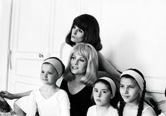 a group of women sitting next to each other in front of a wall with hats on