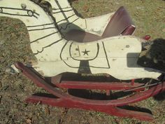 an old rocking horse is sitting in the grass with its shadow on it's back