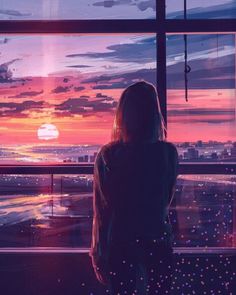 a woman standing in front of a window looking out at the ocean and sunsets