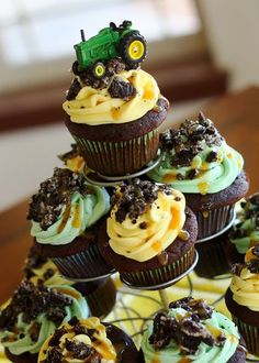 cupcakes with frosting and tractors on them are arranged in the shape of a pyramid