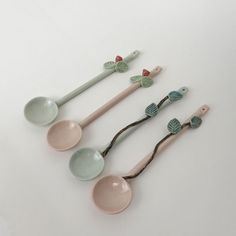 four spoons are lined up in the shape of flowers and leaves on a white surface