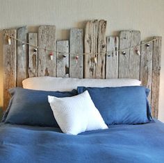 a bed with blue sheets and pillows in a bedroom next to two wooden headboards