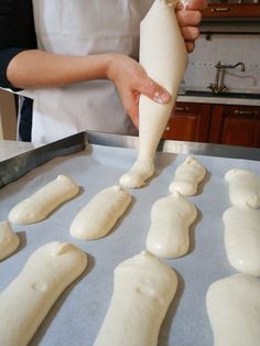 a person is making bread dough on a baking sheet and rolling it into long pieces