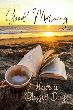 an open book sitting on top of a sandy beach next to a cup of coffee