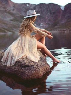 a woman sitting on top of a rock in the water