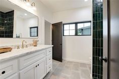 a large bathroom with white cabinets and marble counter tops, along with a walk in shower