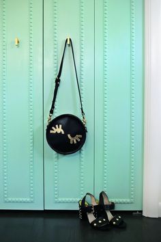 a pair of black shoes sitting in front of a blue door with a purse hanging on it