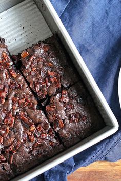 a pan filled with brownies on top of a blue cloth next to a plate