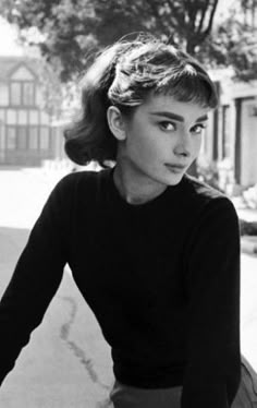 an old black and white photo of a woman on a bicycle