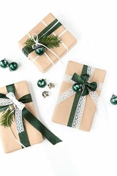 presents wrapped in brown paper with green ribbon and ornaments around them on a white surface