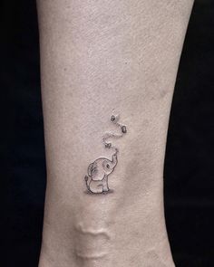 an elephant tattoo on the ankle with bubbles coming out of it's back side