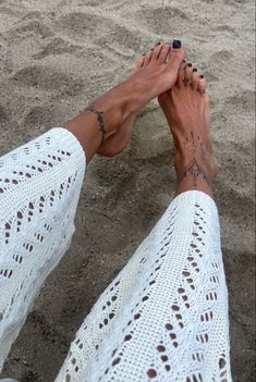 a woman's feet in the sand with her hand on her hip