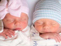 two newborn babies sleeping next to each other wearing knitted hats and swaddles