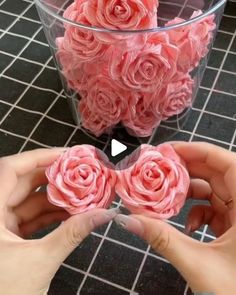 two hands are holding pink flowers in a vase