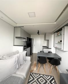 a living room filled with furniture next to a kitchen and dining room table on top of a hard wood floor