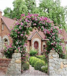 a brick house with pink flowers on the front gate