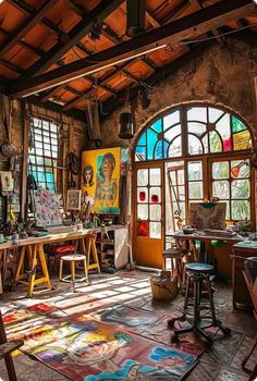 an artist's studio with multiple paintings and stools in front of large windows