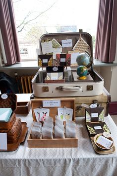 an open suitcase sitting on top of a table filled with cards and other items next to a window