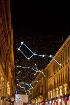 an empty city street at night with christmas lights on the buildings and people walking around