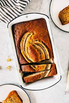 a loaf of pumpkin swirl bread on a plate with two slices cut from the loaf