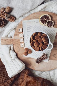 a bowl of dog food next to an open book and some cinnamons on a table