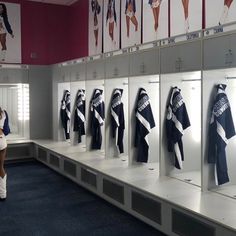 a woman is looking at her cell phone while standing in front of lockers with scarves on them