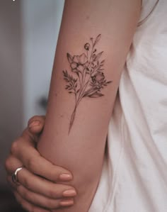 a woman's arm with a flower tattoo on the left side of her arm