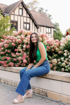 a woman sitting on a ledge in front of flowers