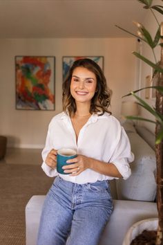 a woman sitting on a couch holding a cup