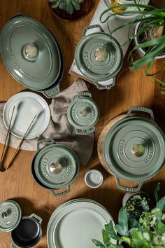 the table is set with dishes, utensils and plants in pots on it