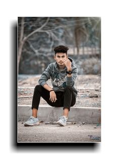 a young man sitting on top of a cement wall