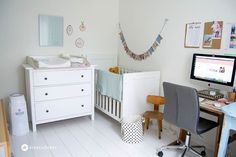 a baby's room with a crib, desk and computer on the wall