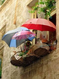 two open umbrellas sitting on the ledge of an old building, one red and one blue