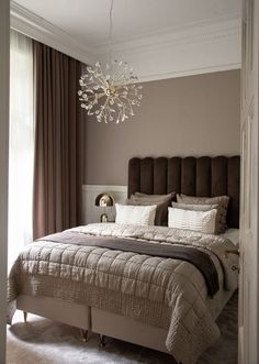 a bedroom with a large bed and a chandelier hanging from it's ceiling