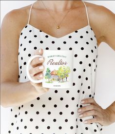 a woman is holding a coffee mug in one hand and wearing a polka dot dress