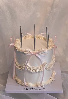 there is a white cake with pink ribbon on the top and two forks sticking out of it